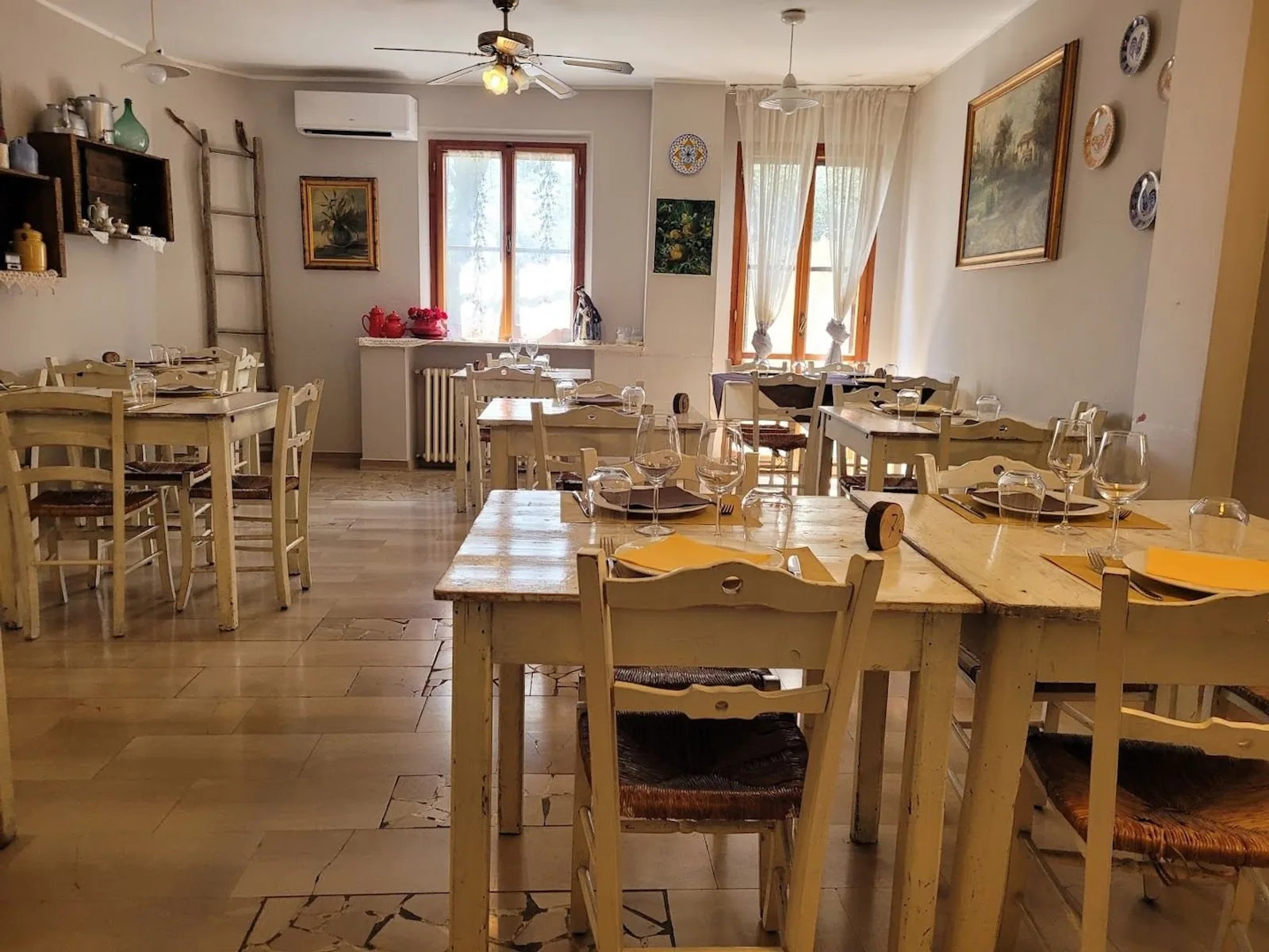La sala dell’osteria con tavoli in legno chiaro e sedie impagliate La sala dell’osteria con tavoli in legno chiaro e sedie impagliate