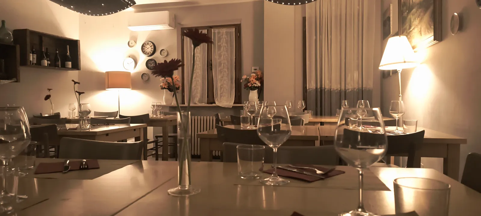 La sala di sera, con i tavoli apparecchiati e la luce calda delle lampade La sala di sera, con i tavoli apparecchiati e la luce calda delle lampade